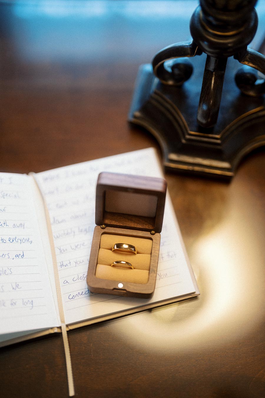 Two rings in a wooden box resting on an open handwritten notebook