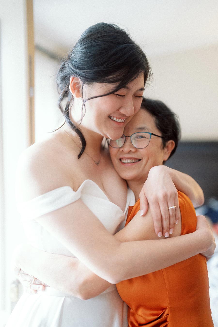 Bride-to-be hugging a smiling woman indoors, showing her engagement ring