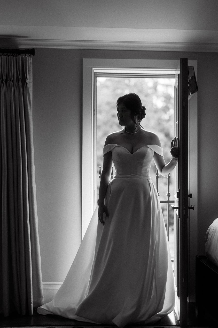 Woman in an off-the-shoulder gown standing silhouetted in an open doorway