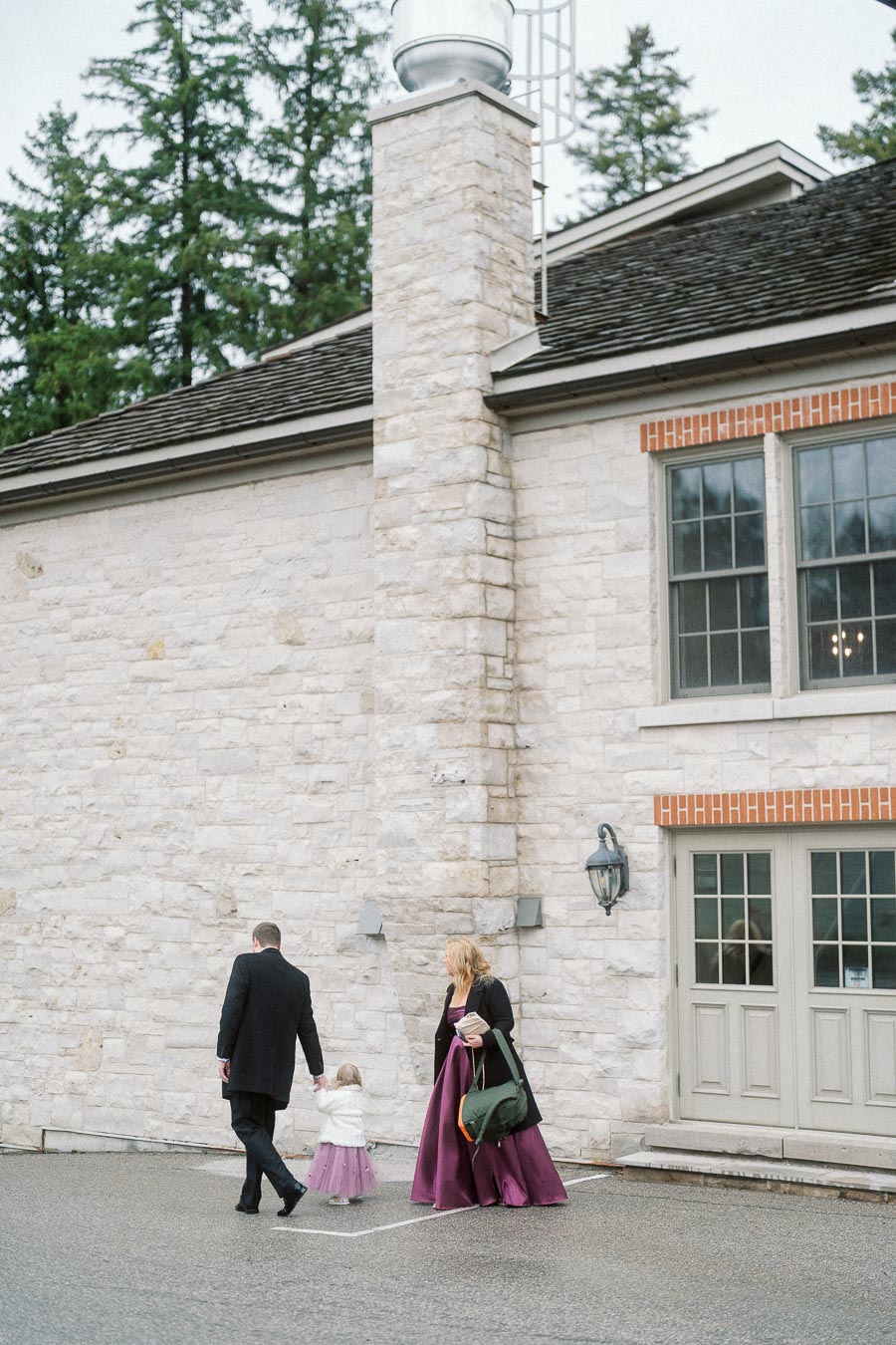 Family walking beside a stone building during an engagement photoshoot