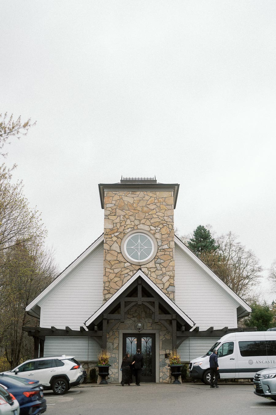 Couple standing at the entrance of a stone chapel-like building during an engagement photoshoot