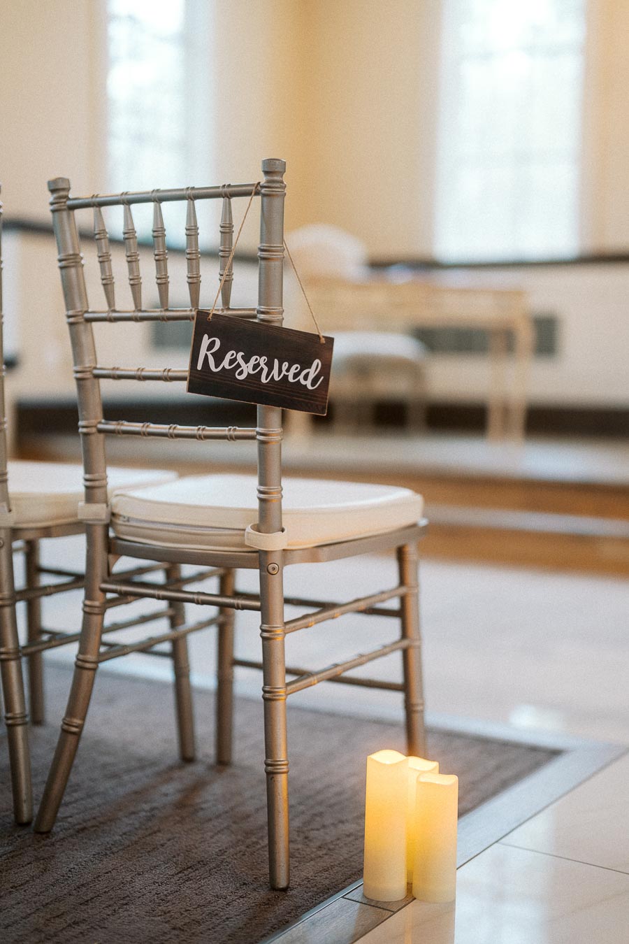 Reserved sign hanging on a chair beside lit candles indoors