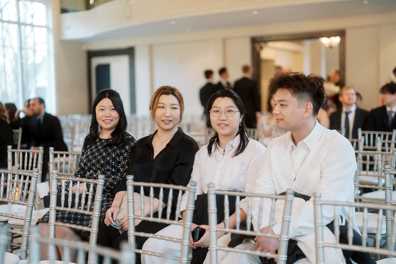 Four guests seated among silver chairs at an indoor engagement event