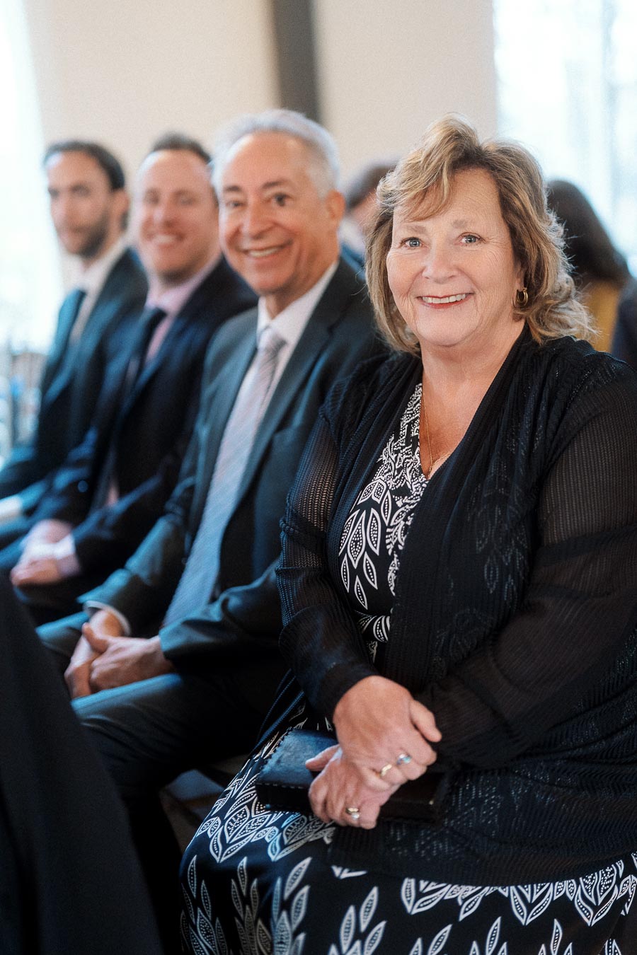 Smiling seated guests dressed formally during an indoor engagement celebration