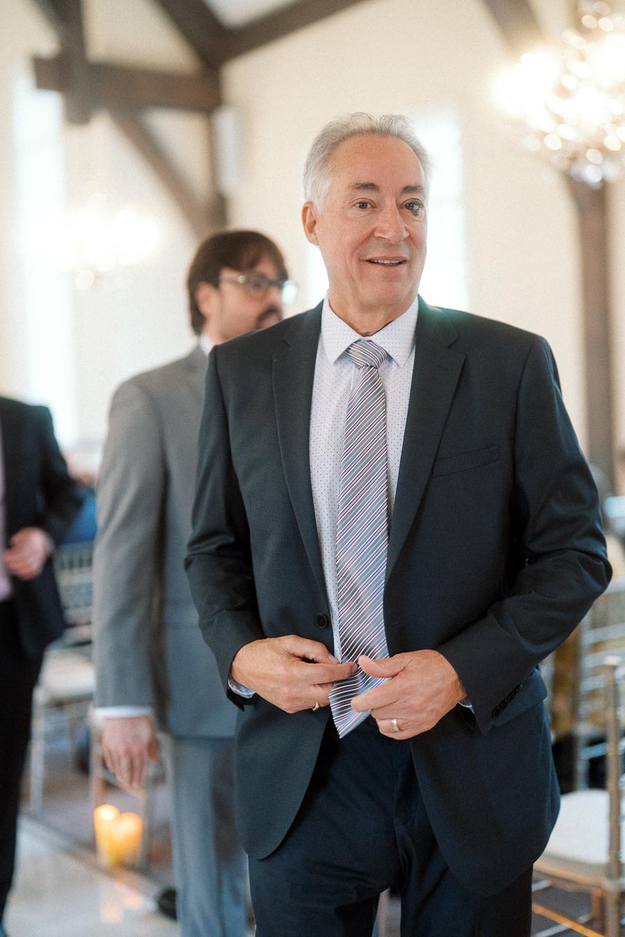 Man in a dark suit adjusting his jacket in an elegant indoor venue