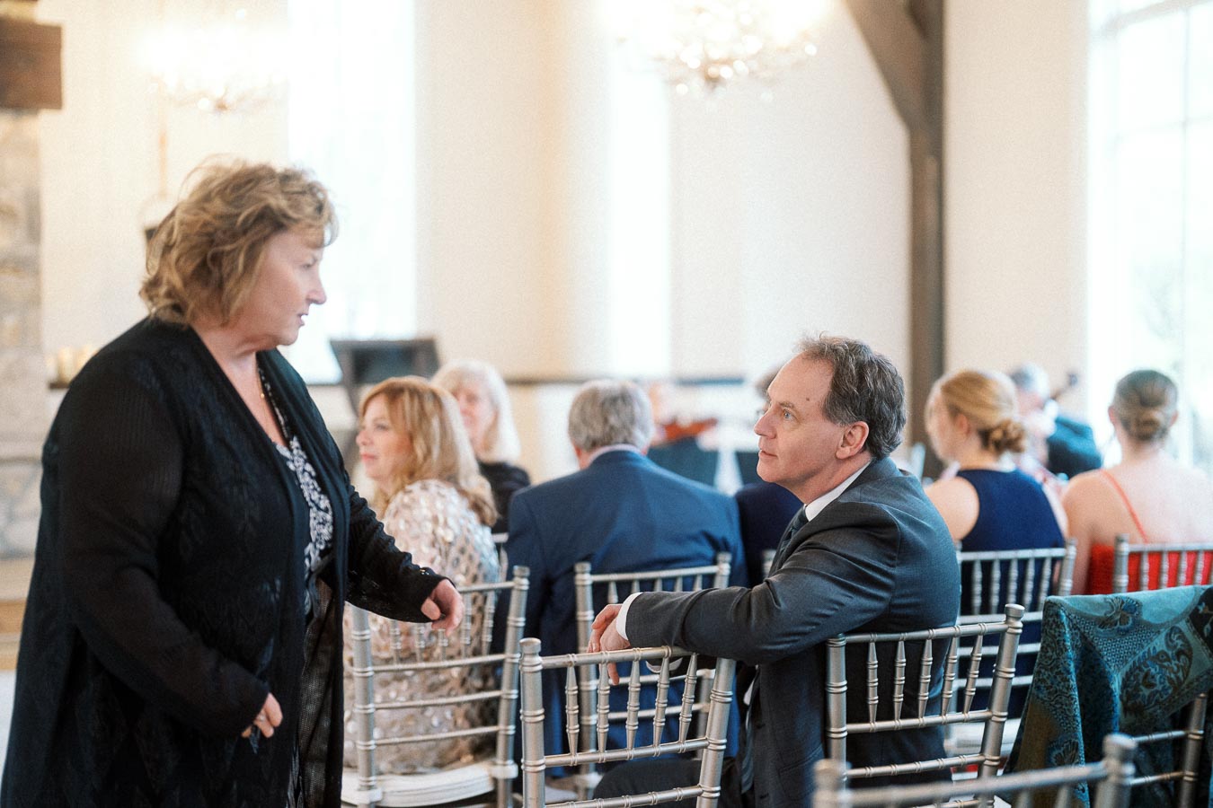 Guests seated on silver chairs during an indoor formal event