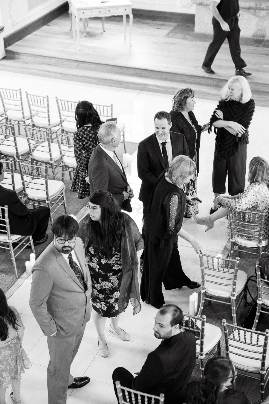 Guests mingling among ceremony chairs in a bright indoor event space