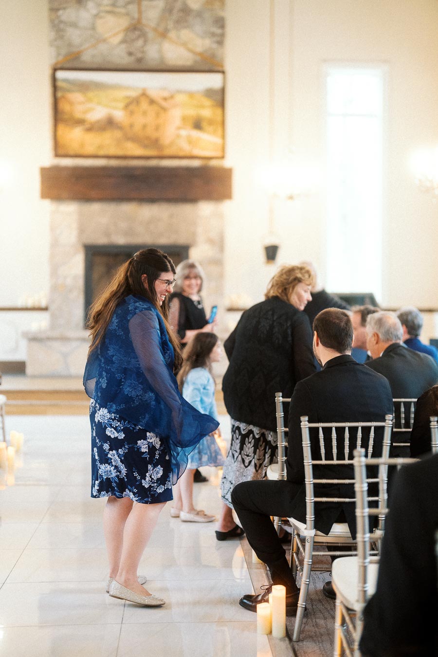 Guests chatting and smiling inside an elegant ceremony room with silver chairs and candles