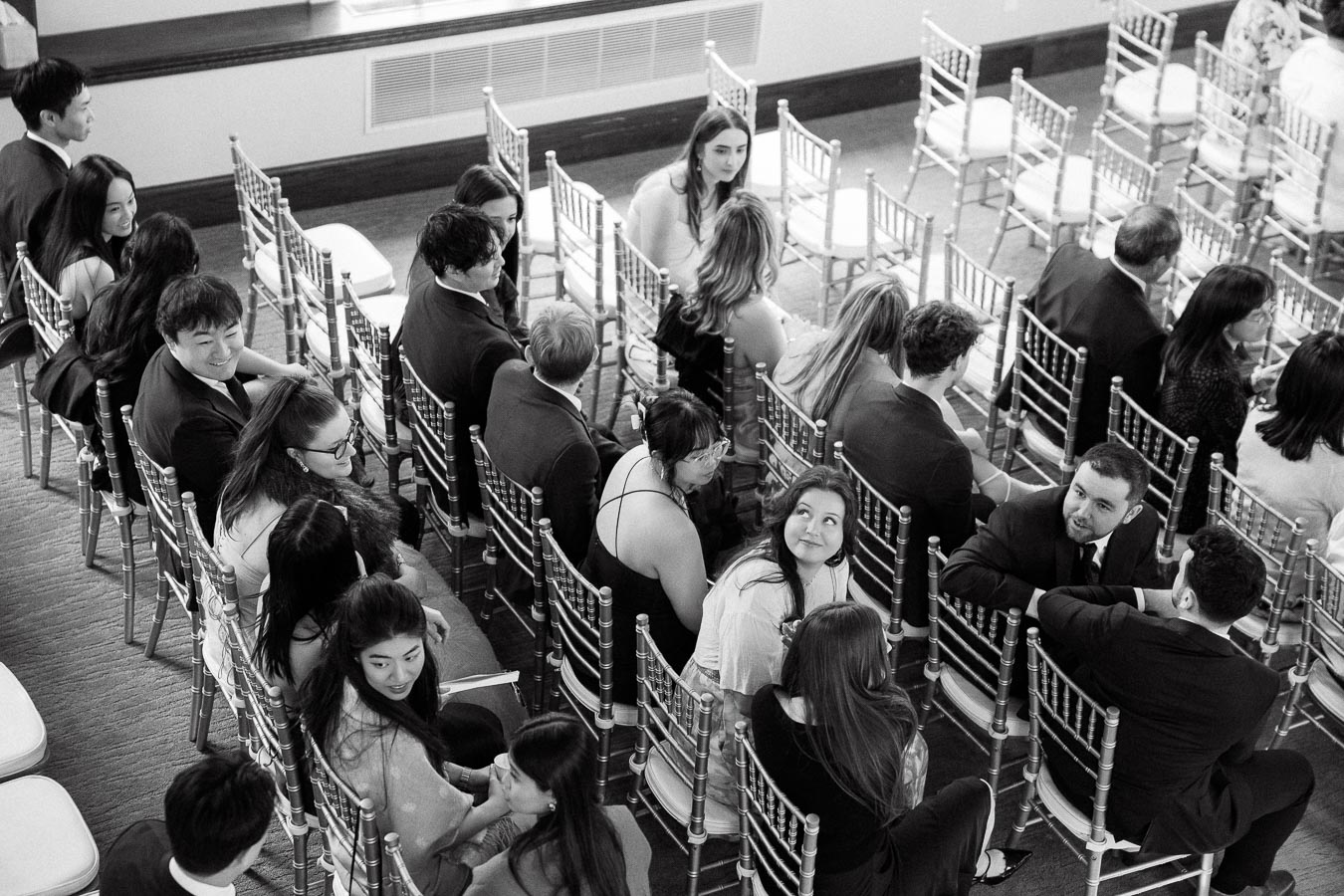 Guests seated in rows of chairs talking before a formal event