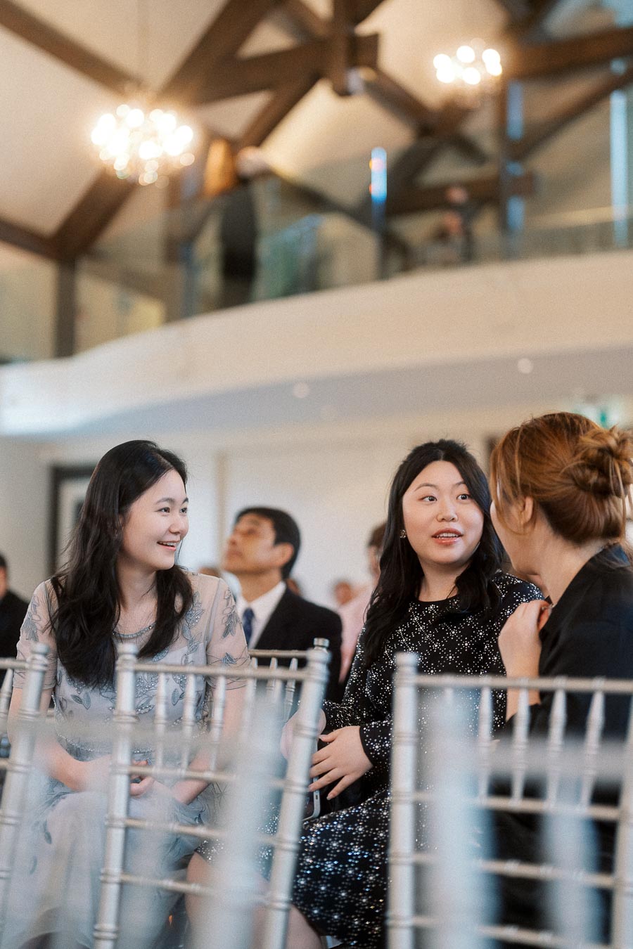 Guests seated on silver chairs chatting inside an elegant indoor venue