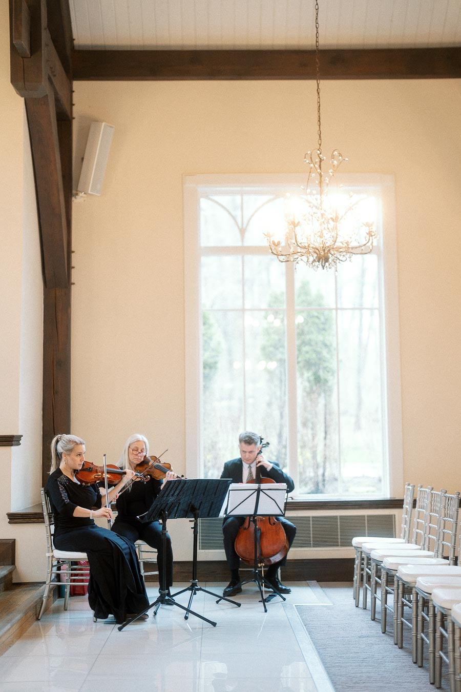 String trio performing beside rows of chairs in a bright indoor event space