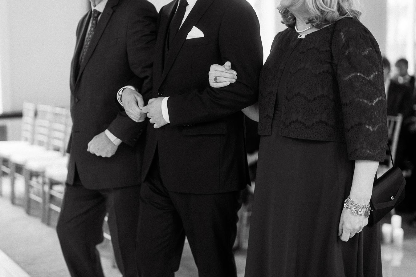 Formally dressed adults standing together, with a woman holding a man's arm.