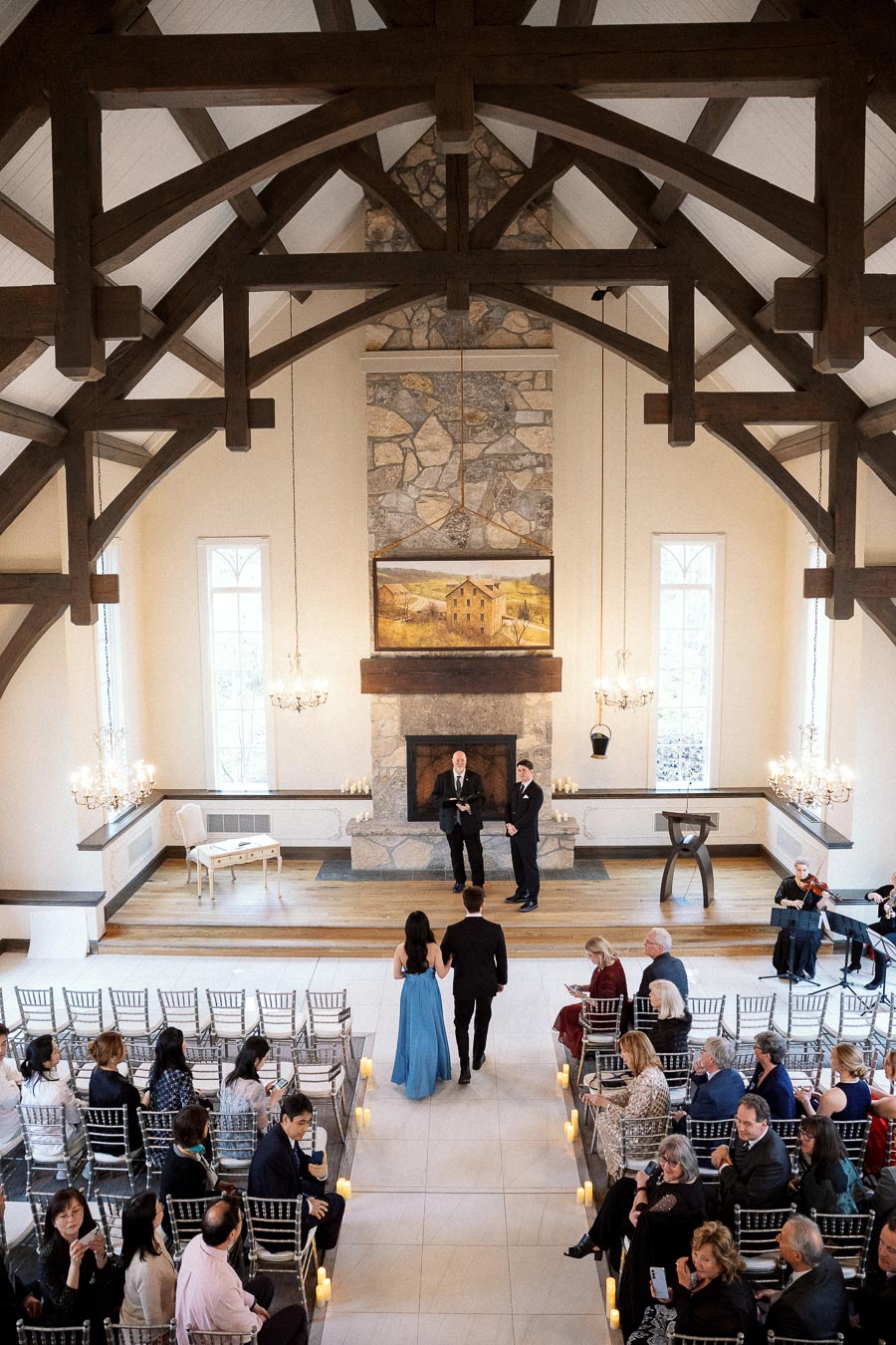 Couple walks down the aisle during an indoor ceremony in a timber-framed chapel.