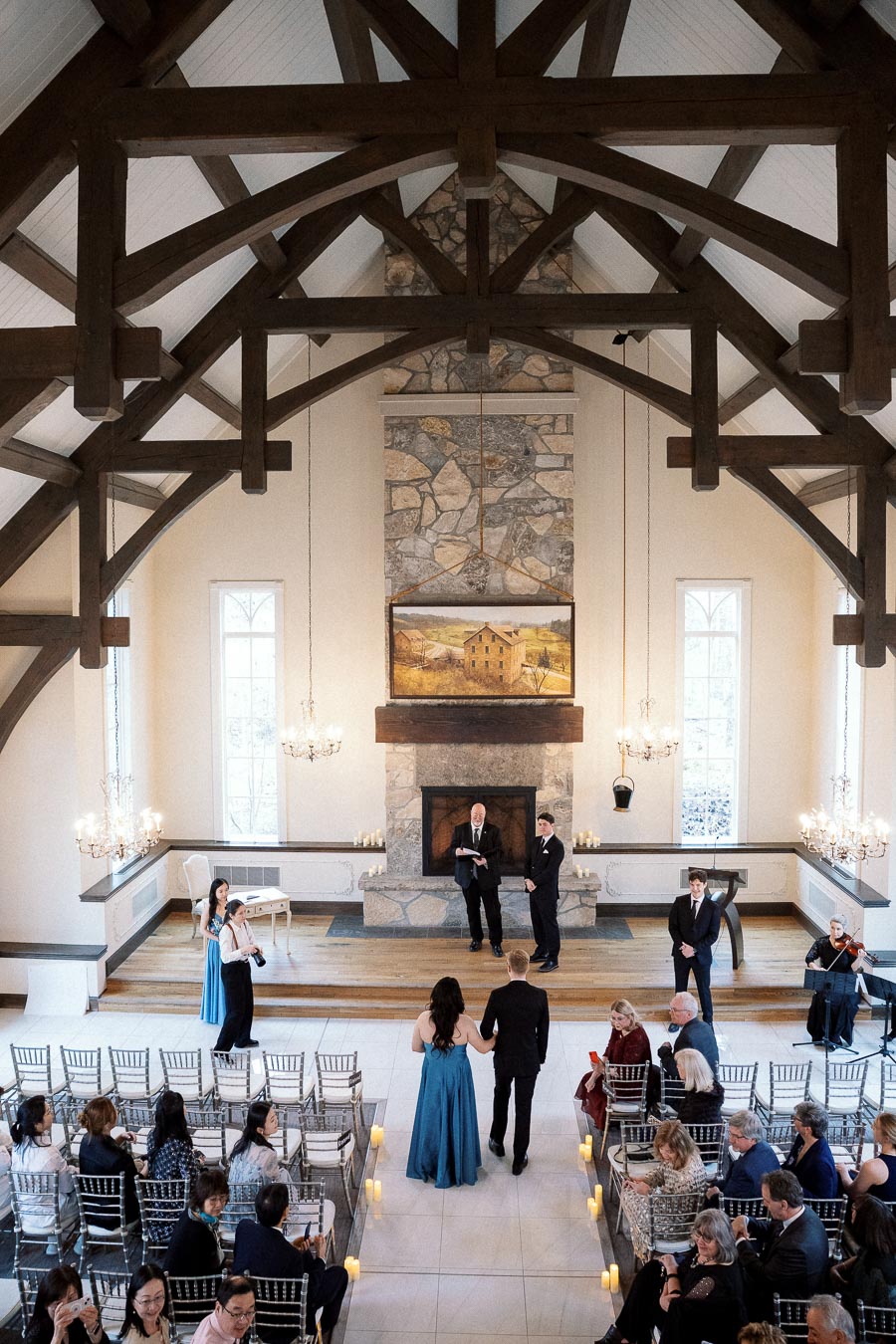 Couple walking down the aisle in a timber-framed ceremony hall with seated guests.