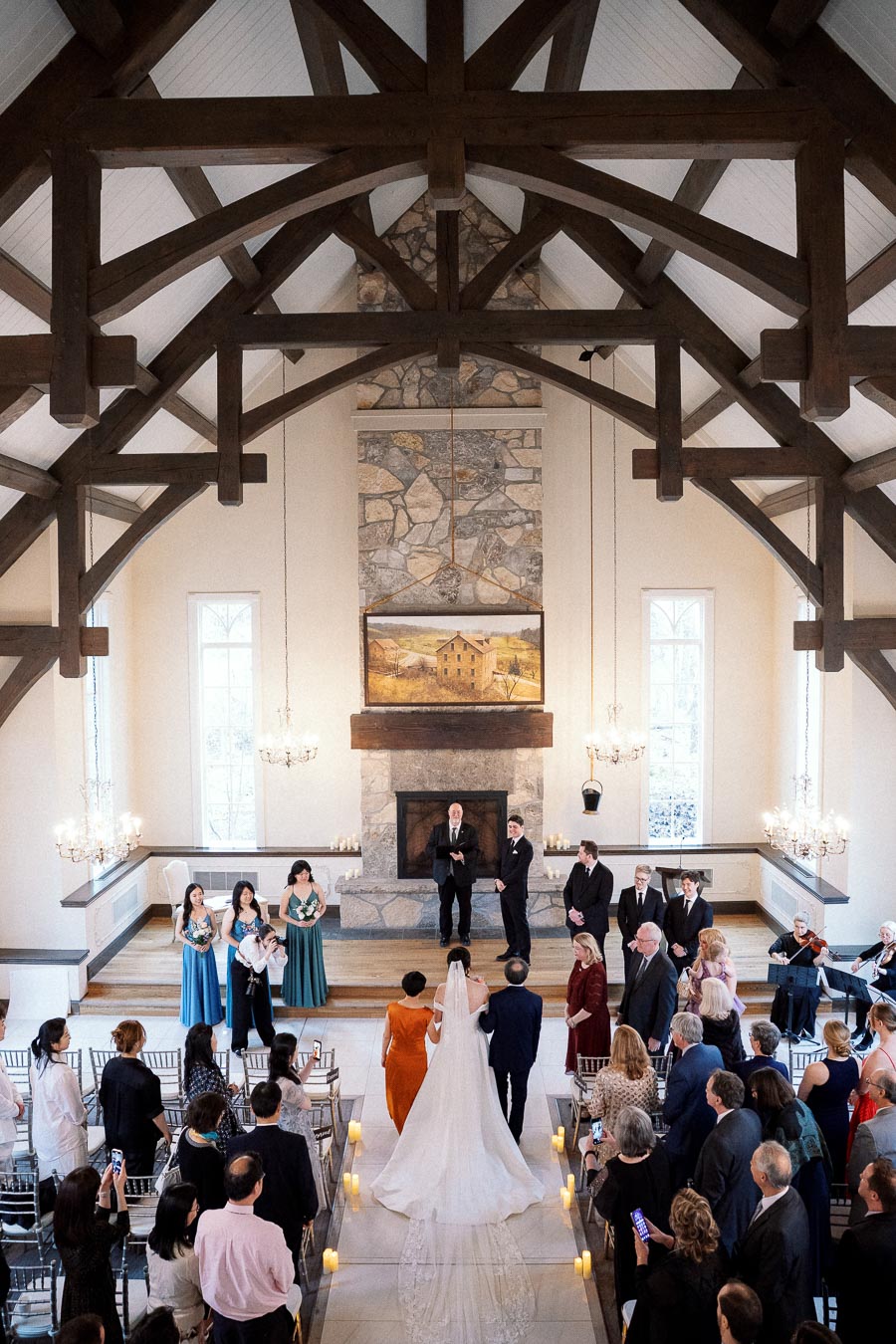 Wedding ceremony inside a chapel with timber beams and guests standing along the aisle