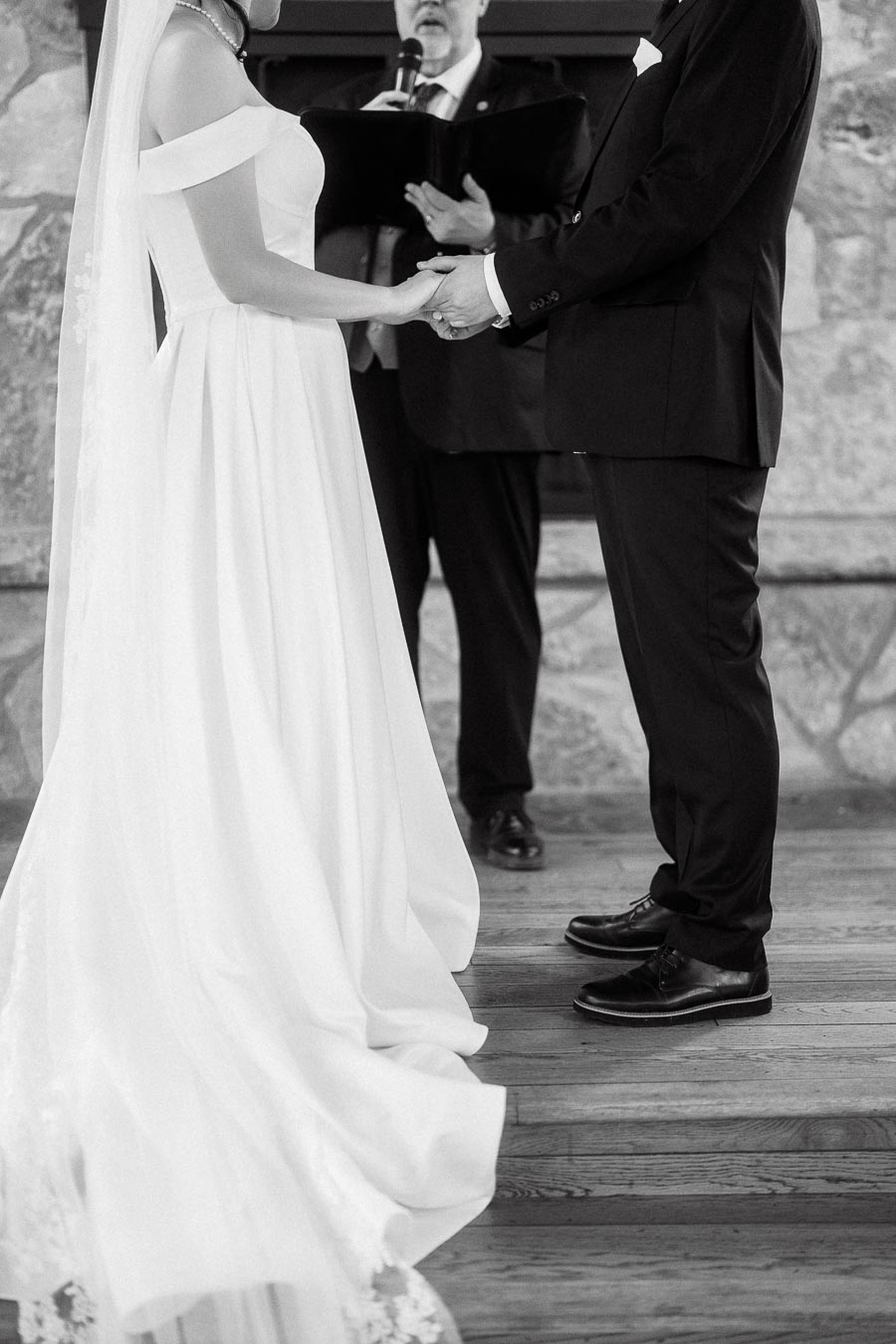 Bride and groom holding hands during a wedding ceremony with an officiant behind them