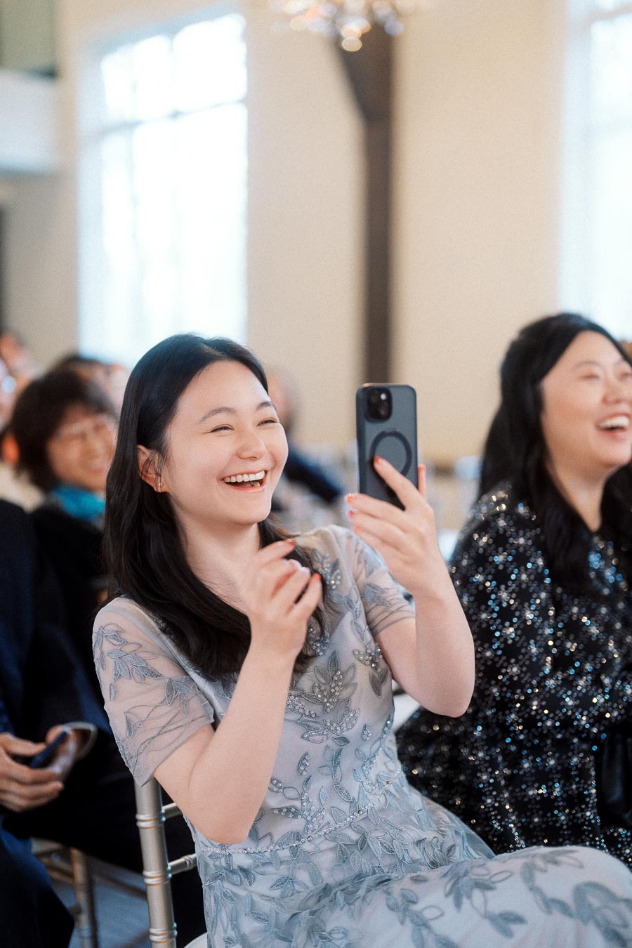 Smiling guest in a floral dress holding up a smartphone indoors