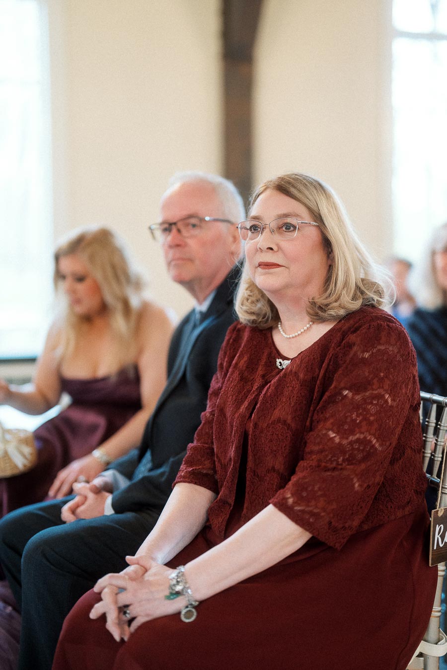 Seated guests in formal attire watching an indoor ceremony