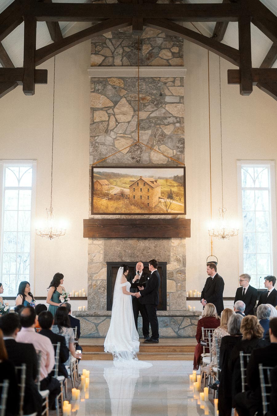 Couple exchanging vows during an indoor wedding ceremony in front of a stone fireplace