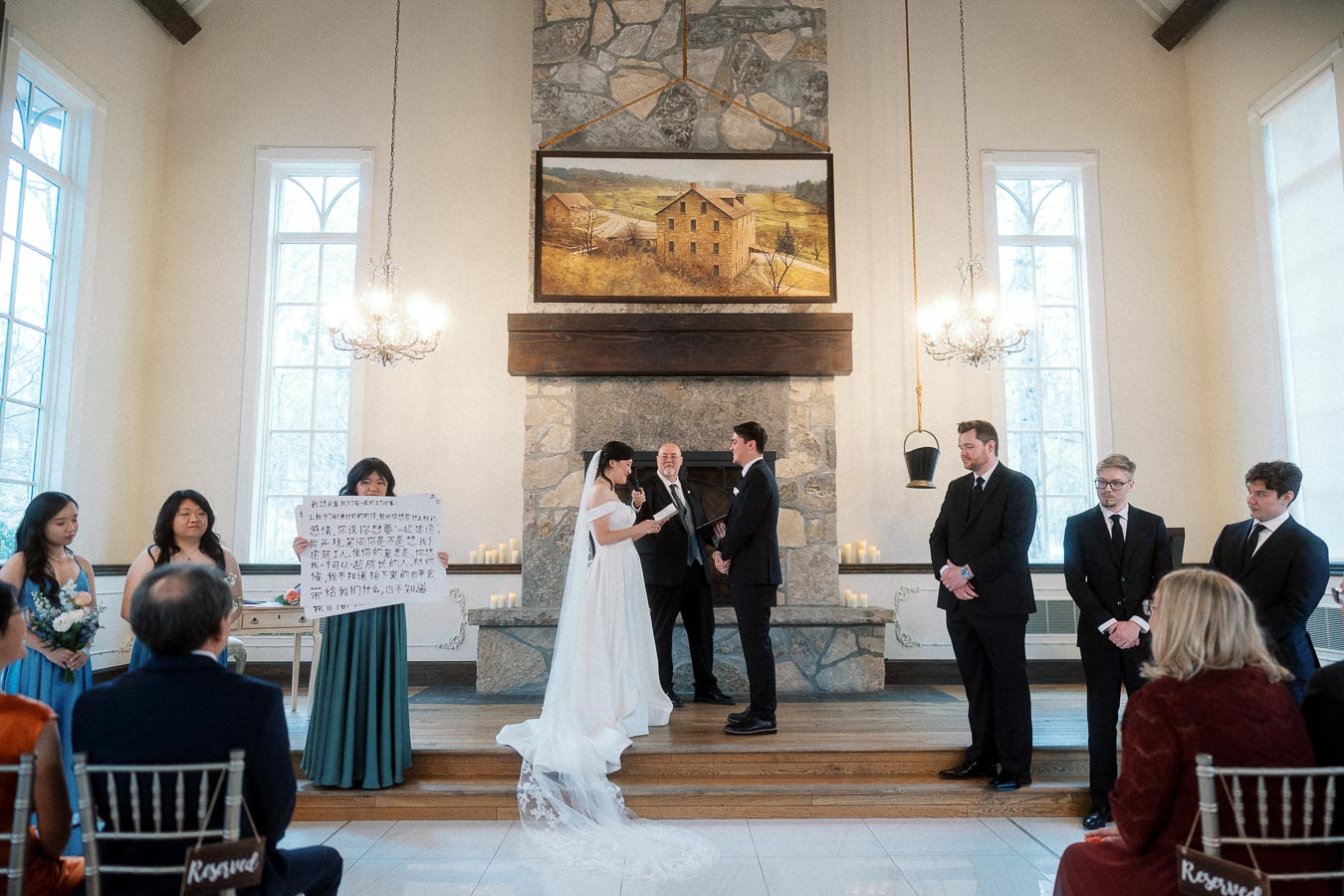 Couple exchanging vows during an indoor wedding ceremony by a stone fireplace.