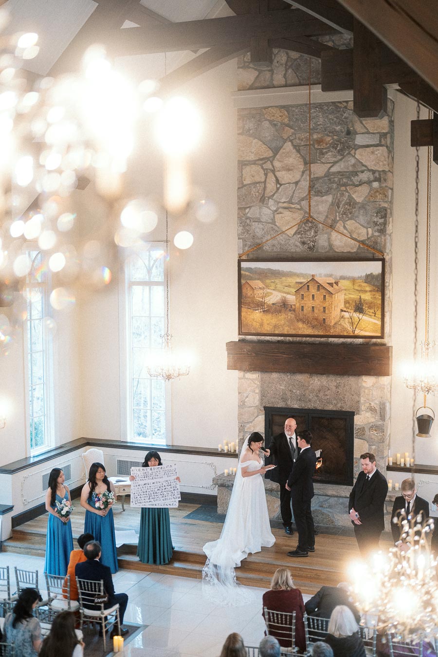Couple exchanging vows during an indoor wedding ceremony beside a stone fireplace.