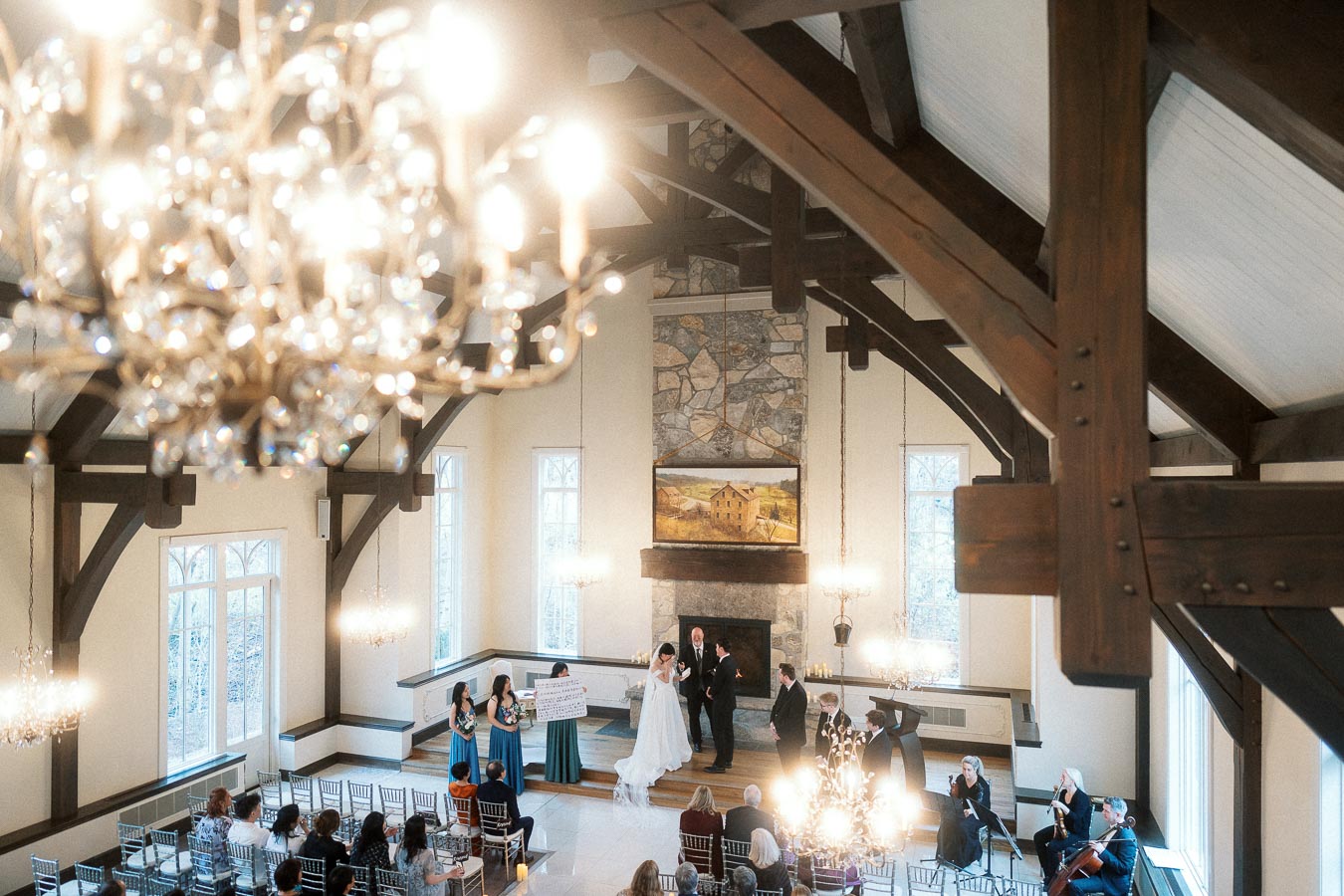 Indoor wedding ceremony in a vaulted timber chapel with chandeliers and seated guests