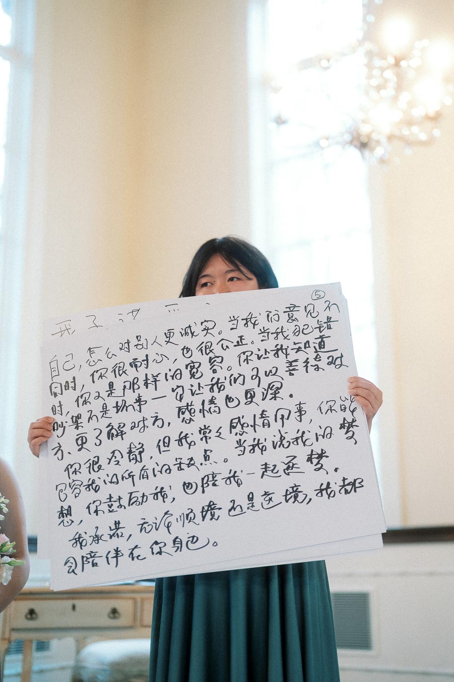 Woman holding a large handwritten sign during an indoor engagement photoshoot