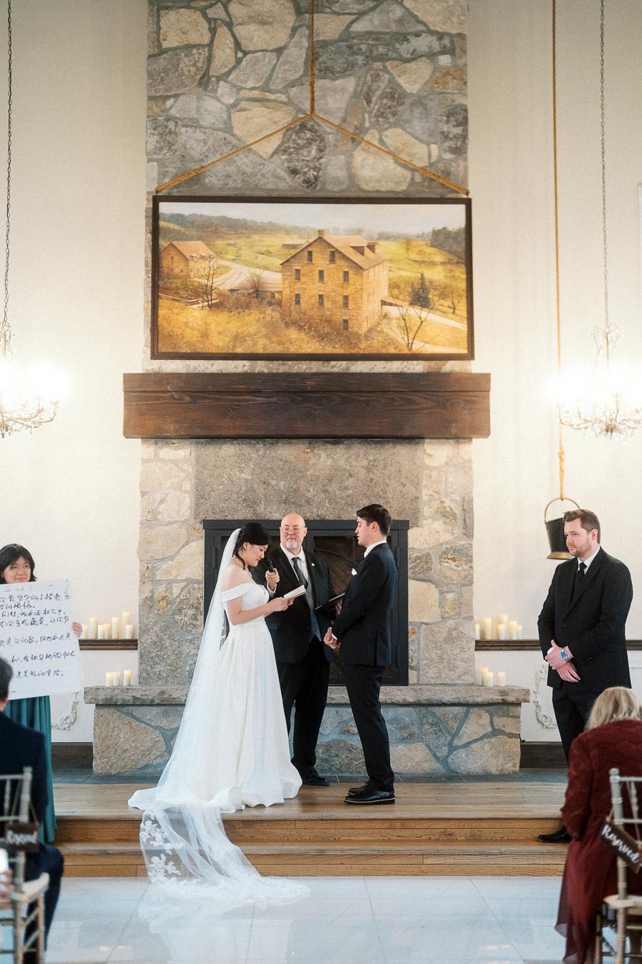 Couple exchanging vows during an indoor wedding ceremony by a stone fireplace