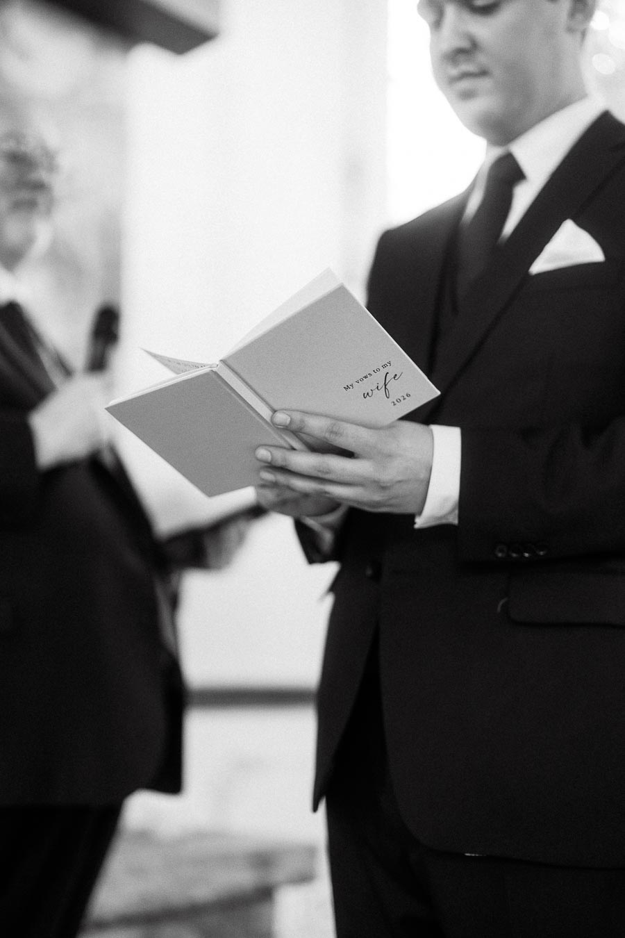 Man in a suit holding a vow book during a ceremony