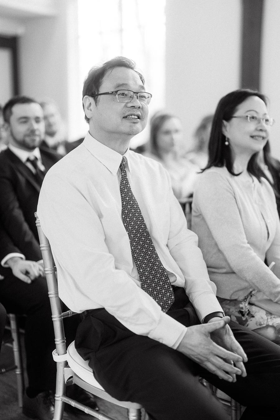 Guests seated indoors during a formal ceremony, watching attentively.