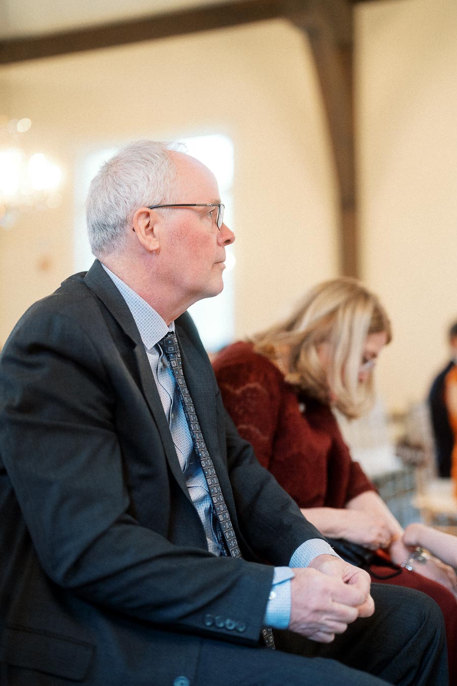 Man in a suit seated indoors during an engagement gathering