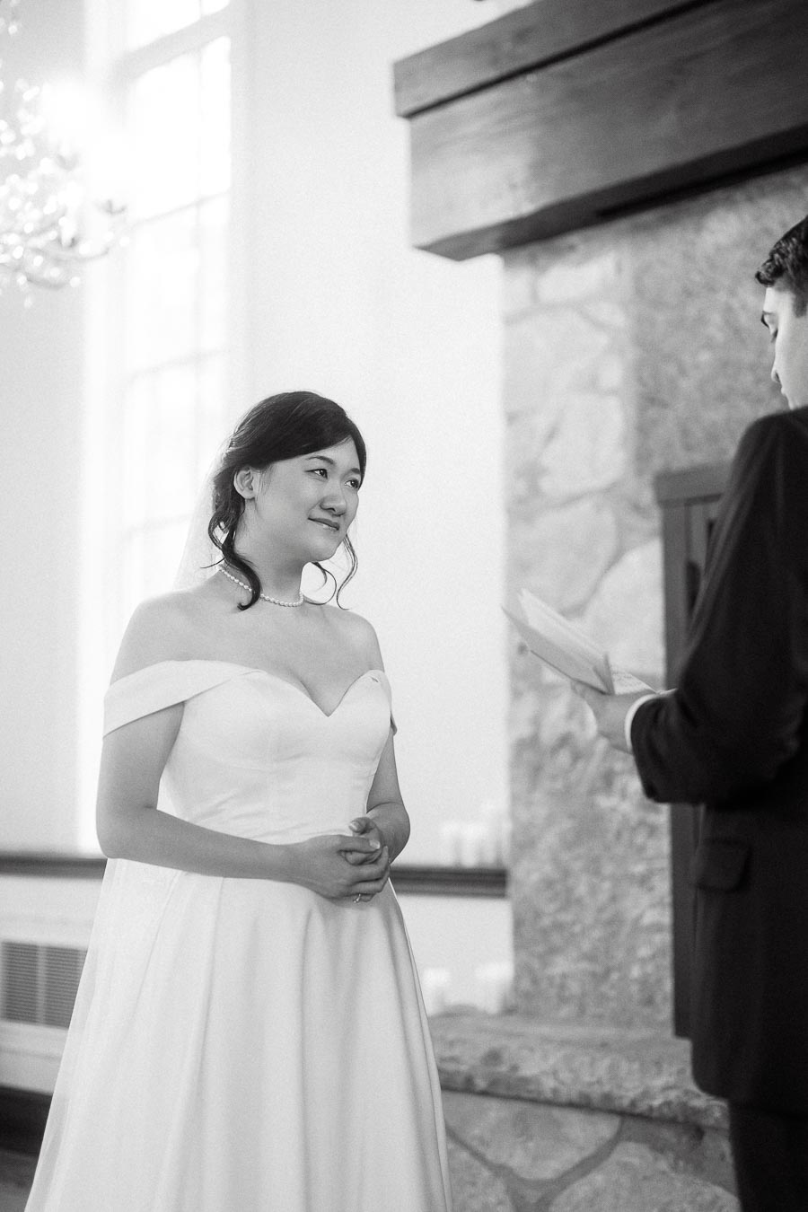 Couple exchanging vows indoors beside a stone fireplace during an engagement-style portrait session