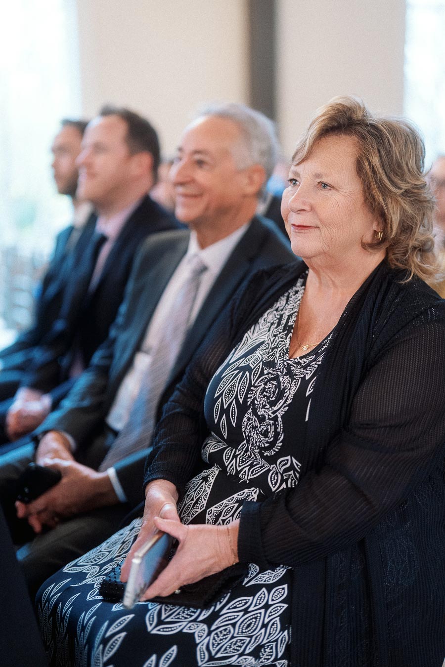 Guests seated indoors, watching attentively during an engagement celebration