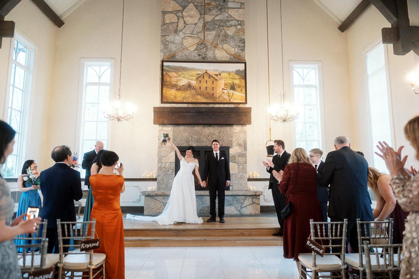 Newlyweds hold hands and celebrate at the altar as guests applaud.