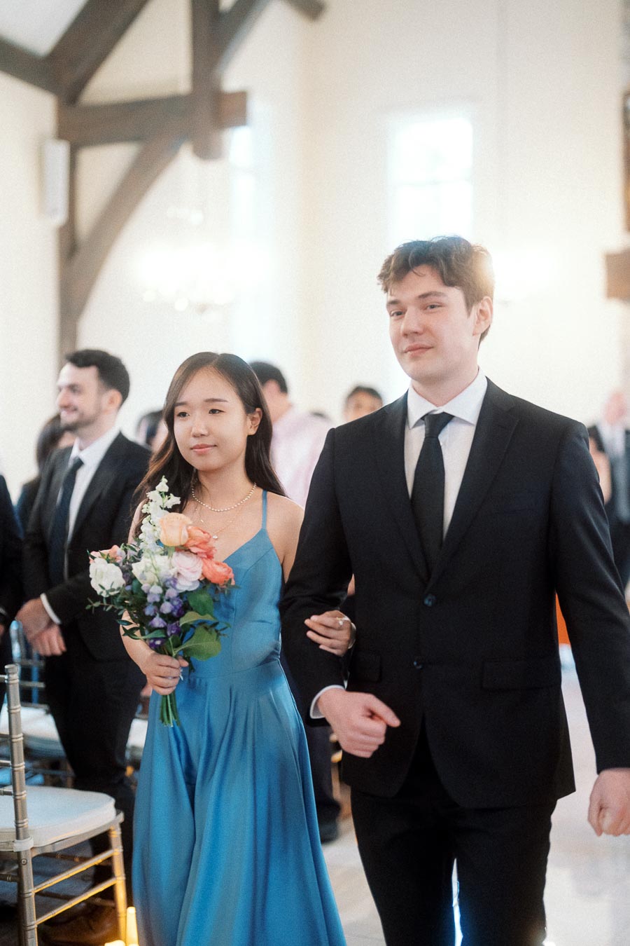 Couple walking arm in arm indoors, one holding a bouquet