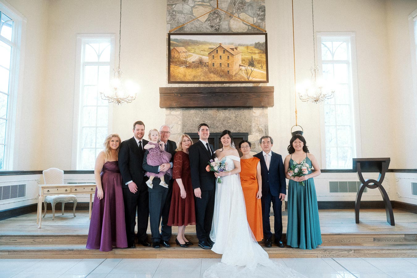 Wedding couple posing with family and attendants in a bright ceremony room.