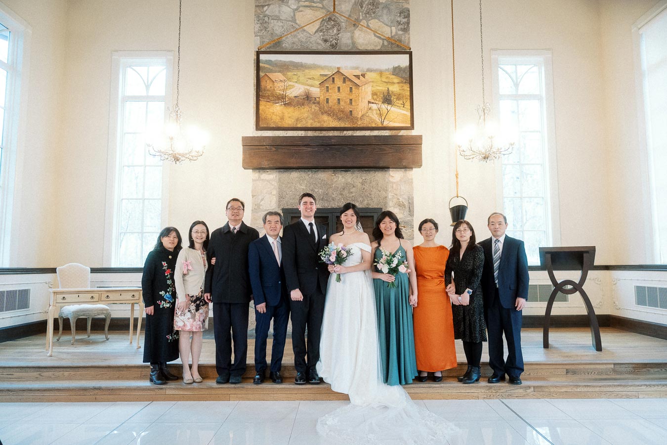 Wedding couple posing with family inside a bright ceremony hall.