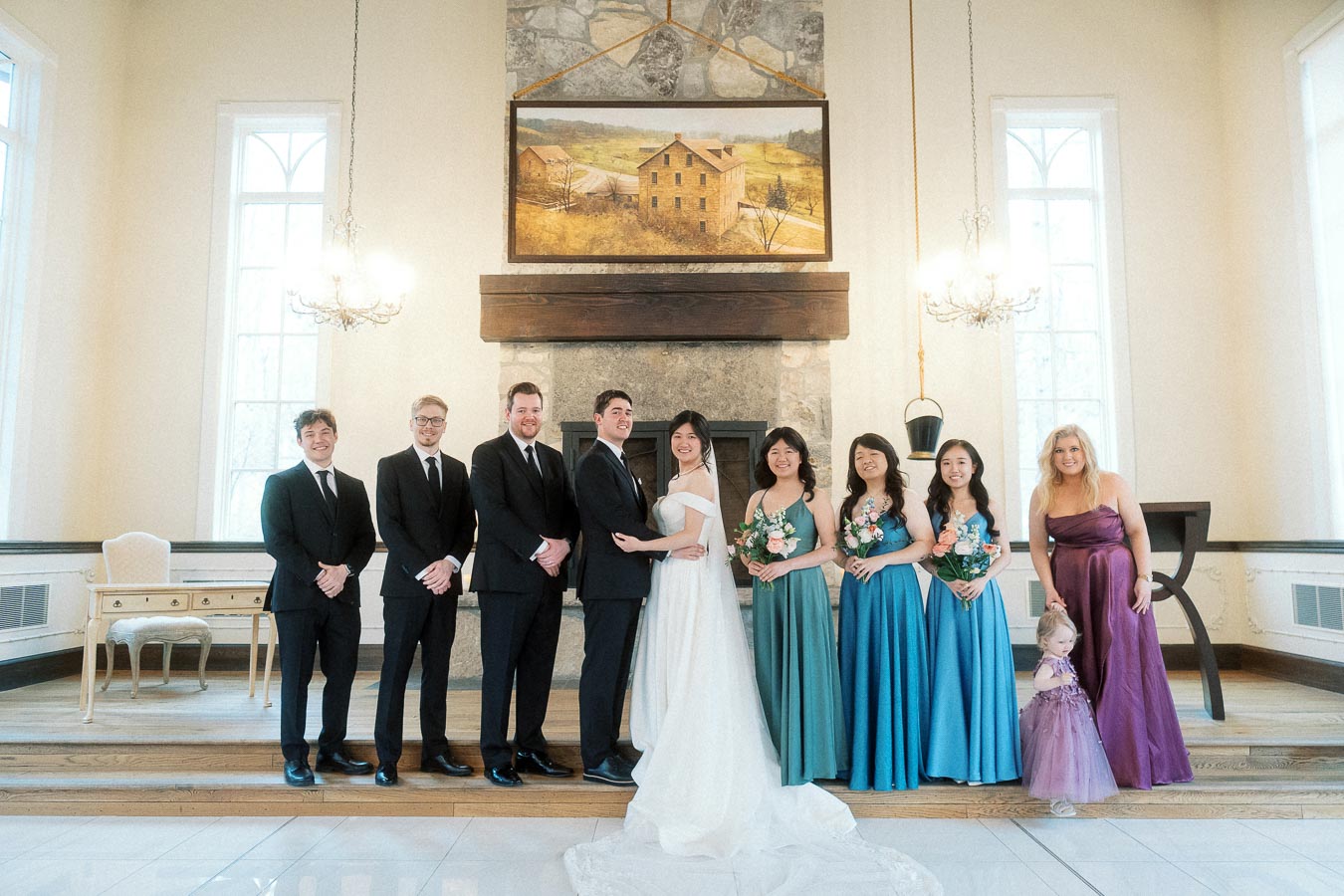 Wedding couple standing with attendants and a child in a bright indoor ceremony space