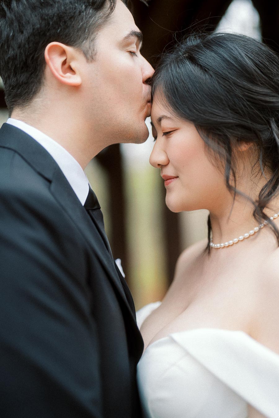 Couple in formal attire sharing a gentle forehead kiss