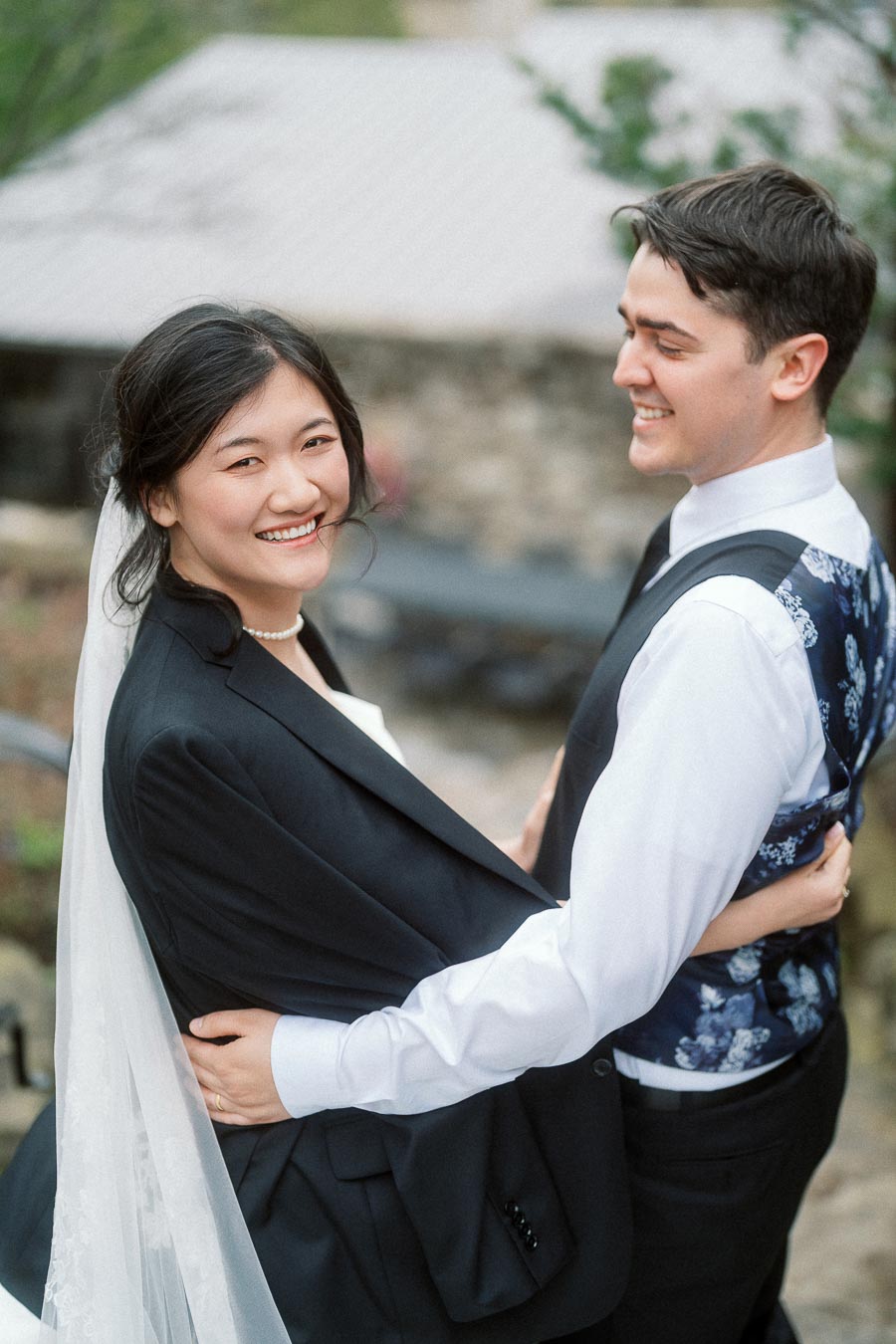 Couple embracing outdoors, with the woman smiling toward the camera.
