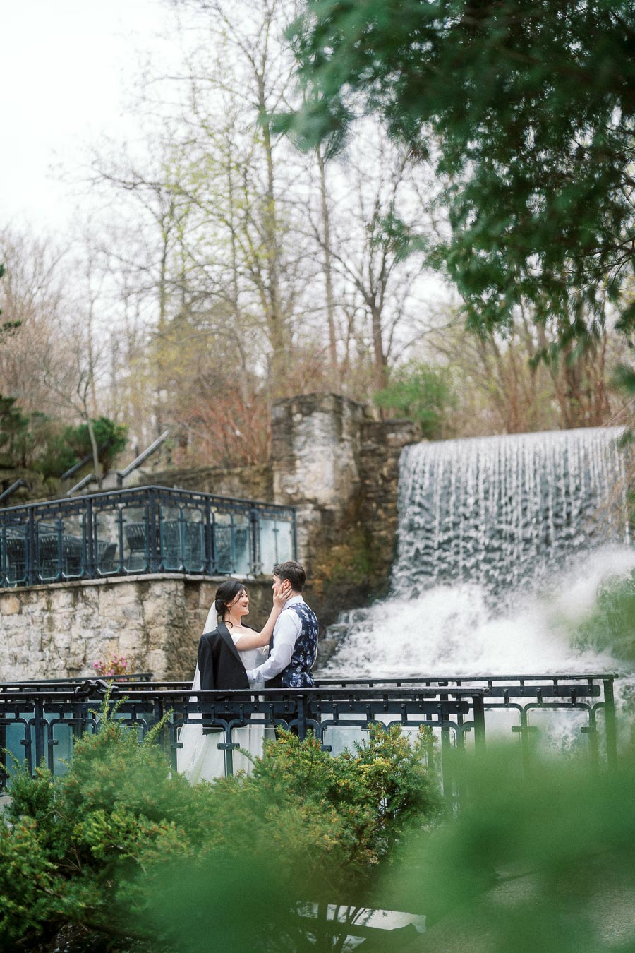 Couple standing together by a waterfall during an engagement photoshoot