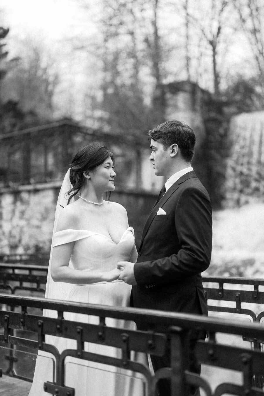 Couple in wedding attire holding hands on a bridge during an engagement photoshoot