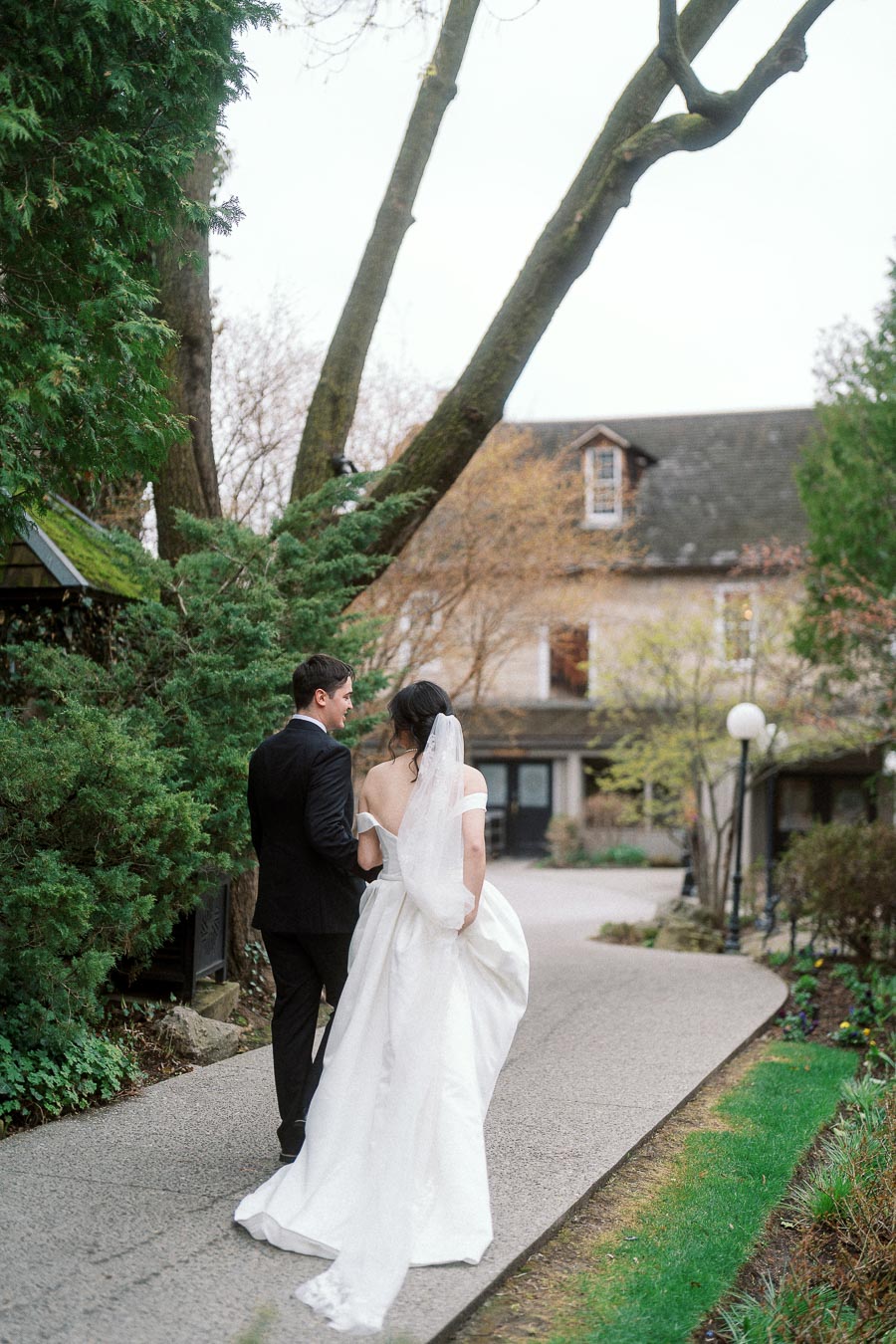 Bride and groom walking arm in arm along a garden path