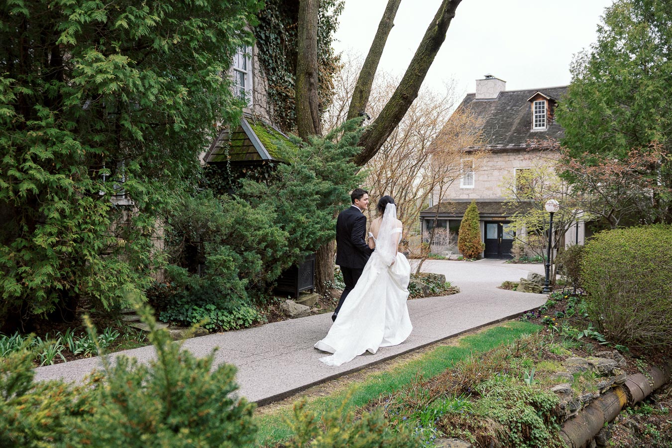 Couple in wedding attire walking together along a garden path