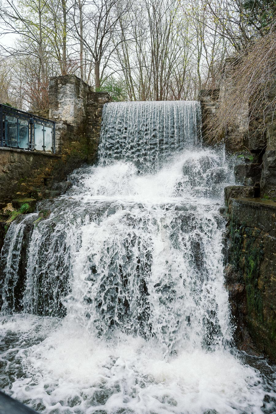 Tiered waterfall rushing over stone walls in a wooded setting