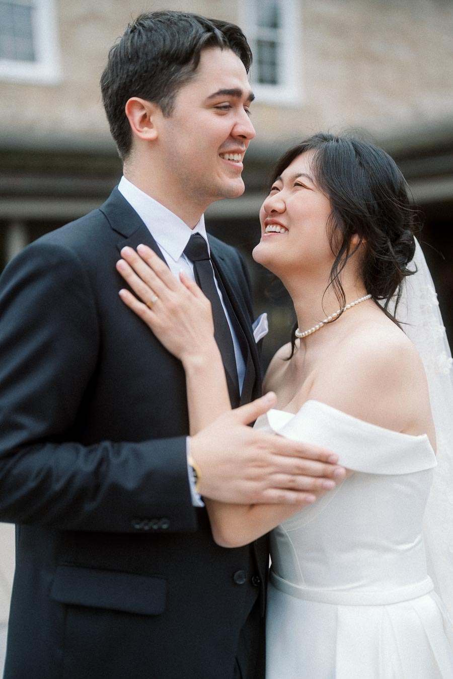 Couple in wedding attire smiling together during a close portrait outdoors