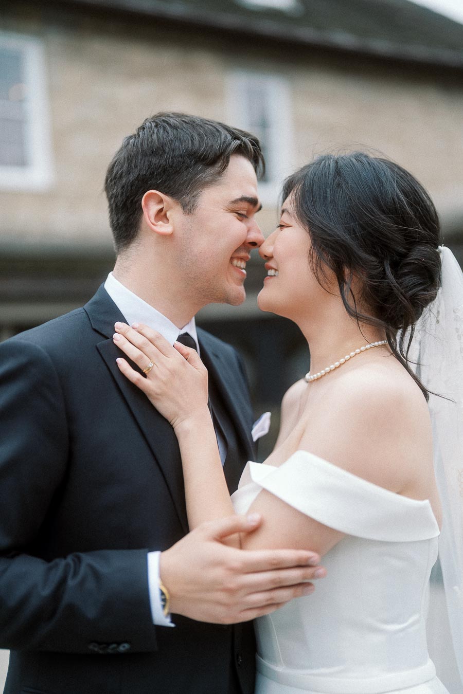 Couple in wedding attire smiling nose to nose outdoors