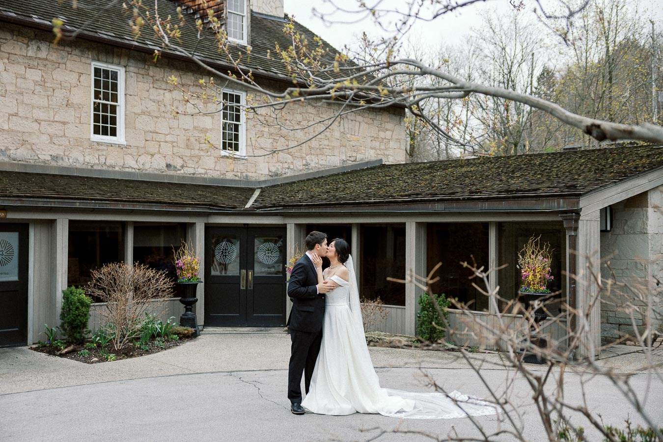 Couple in formal attire kissing outside a stone building during an engagement photoshoot