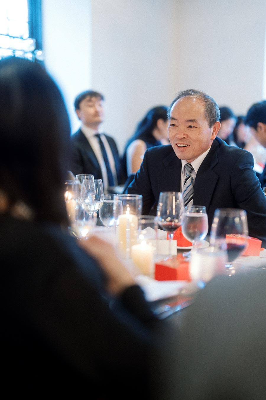 Man in a suit smiling during a candlelit formal dinner with guests