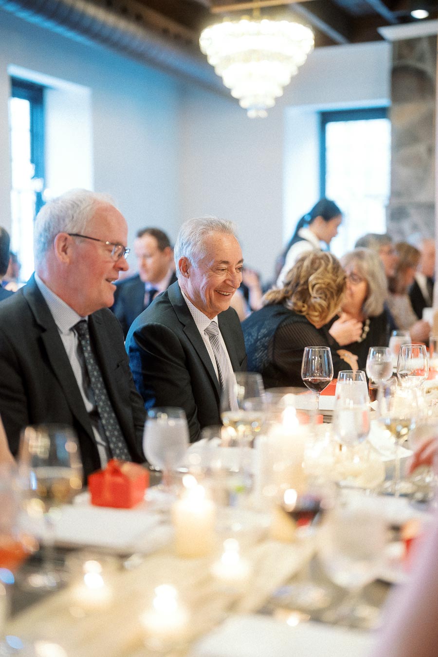 Guests in formal attire smiling at a candlelit reception table.
